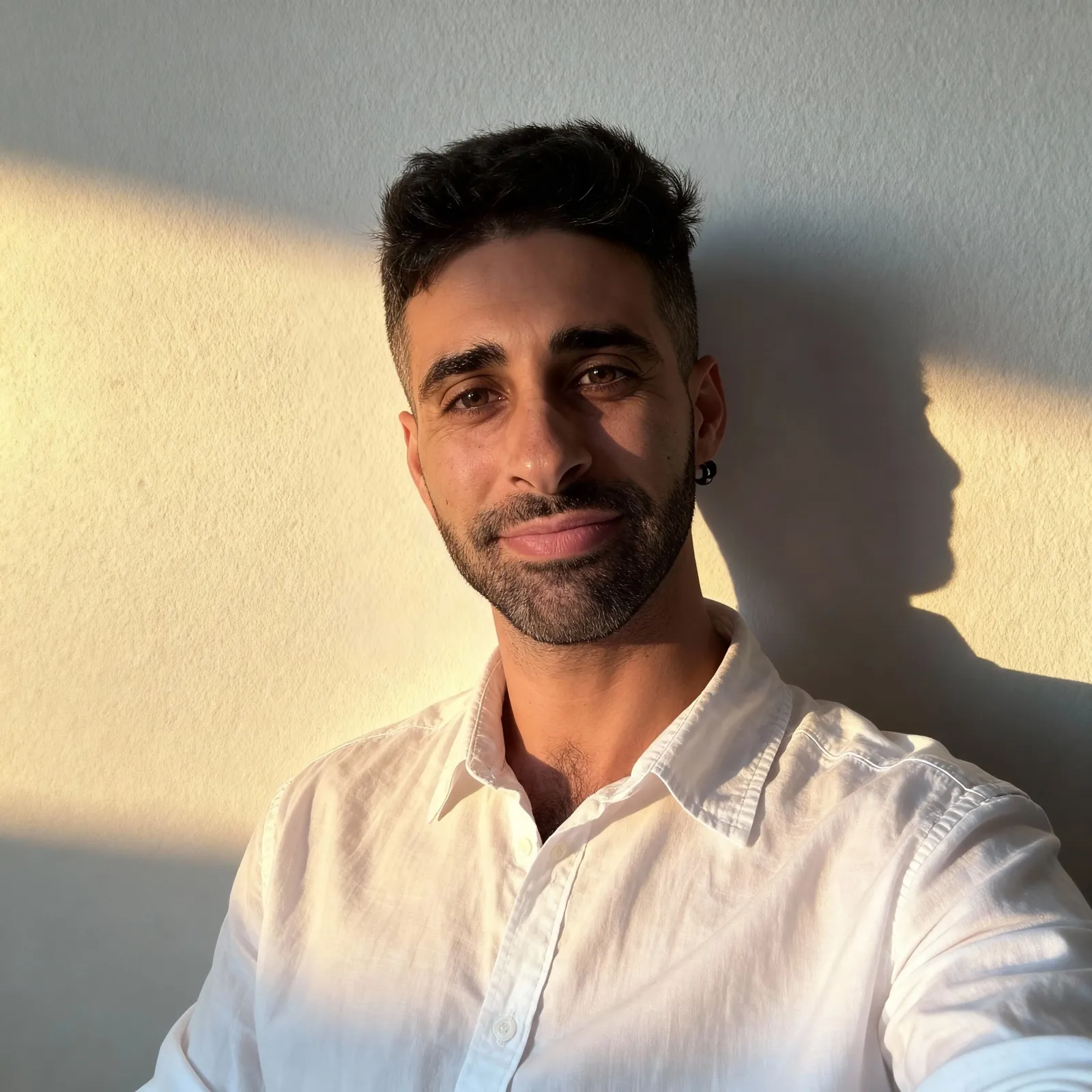 Oscar Penalva, fundador de CaffeOS, con camisa blanca junto a una pared iluminada por el sol.
